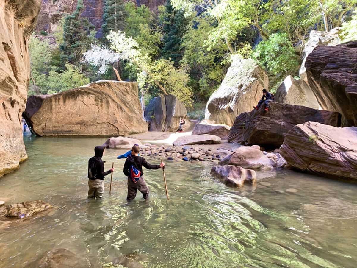 People hiking through river on a visit to Utah