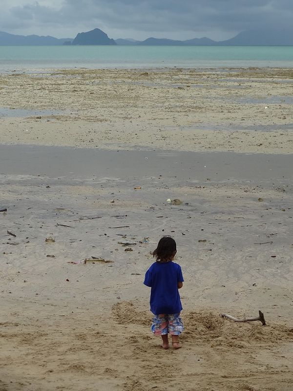 Wet but warm. A child plays on the beach between rain showers on Ko Siray.